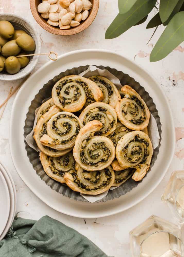 puff pastry pinwheel appetizers with spinach and artichoke filling, piled on plate.