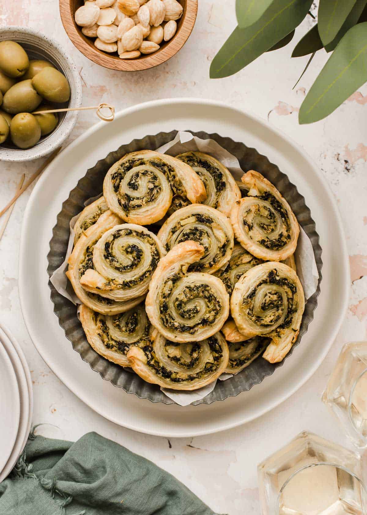 puff pastry pinwheel appetizers with spinach and artichoke filling, piled on plate.