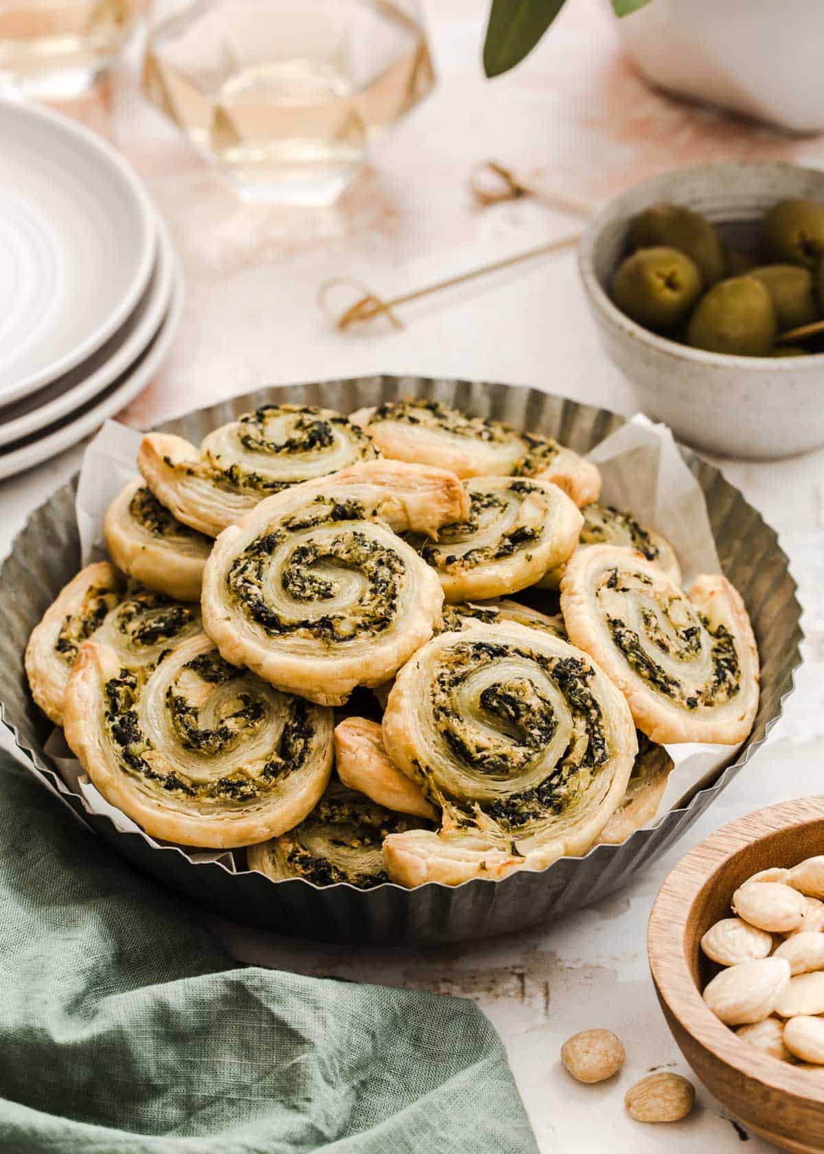 puff pastry pinwheel appetizers with spinach and artichoke filling, piled on plate.