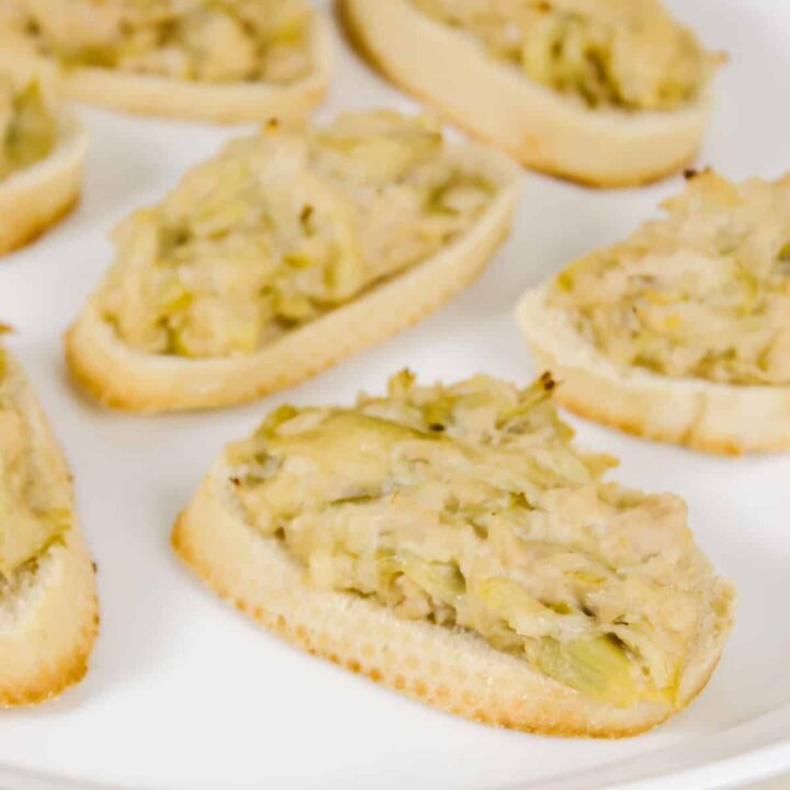 appetizer crostini with chicken and artichoke mixture on top.