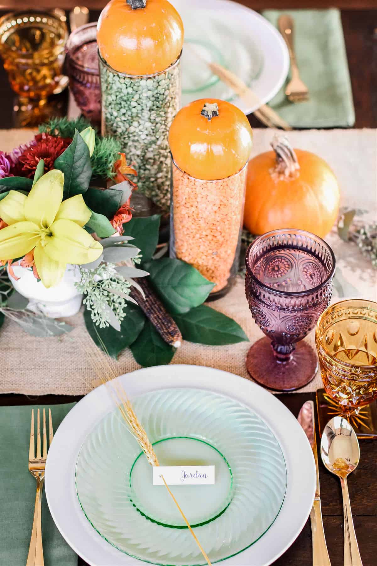 Thanksgiving place setting with green plate, and centerpiece of flowers and pumpkins