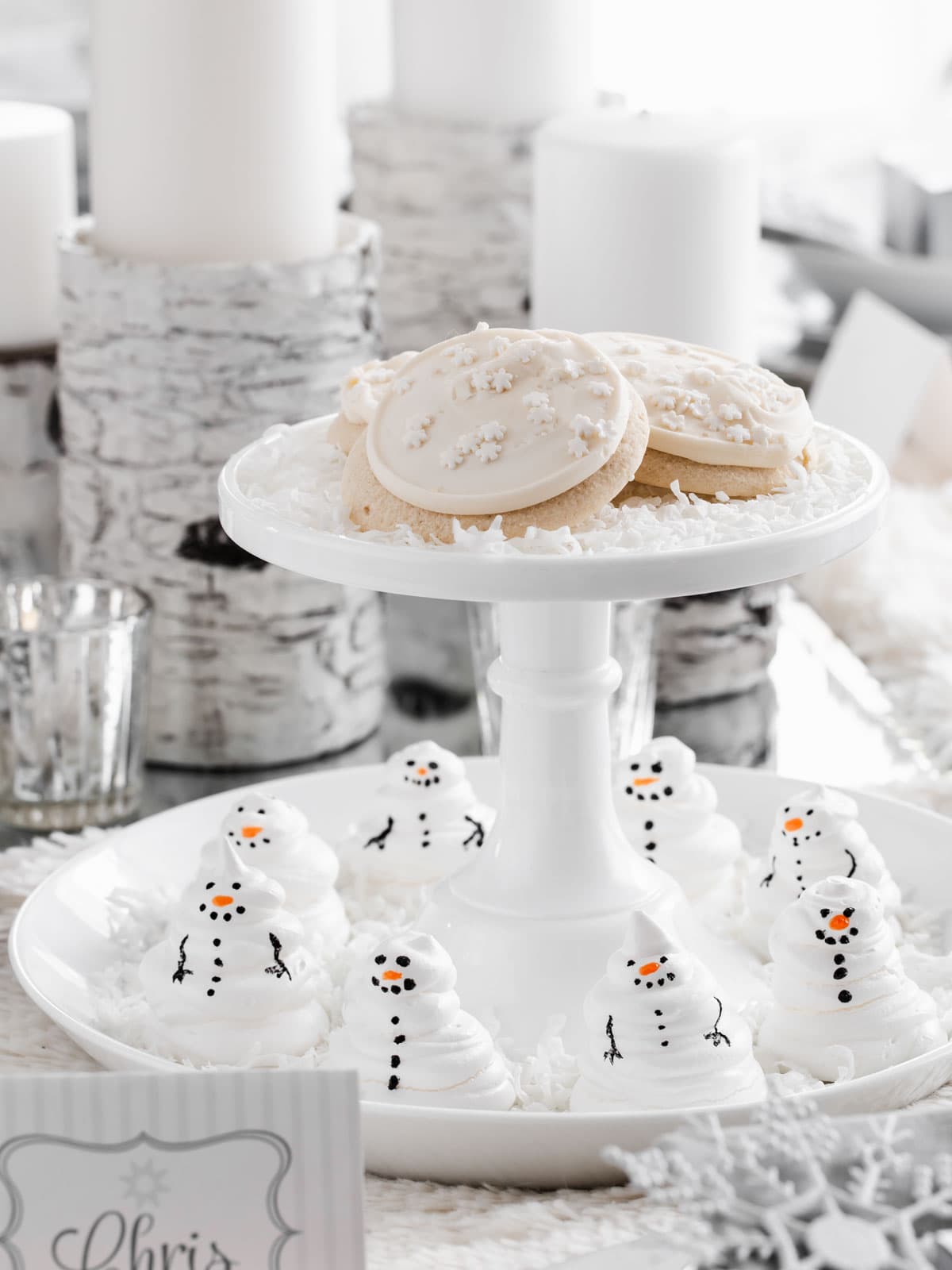 two-tiered server with cookies on top and snowman meringues on bottom.