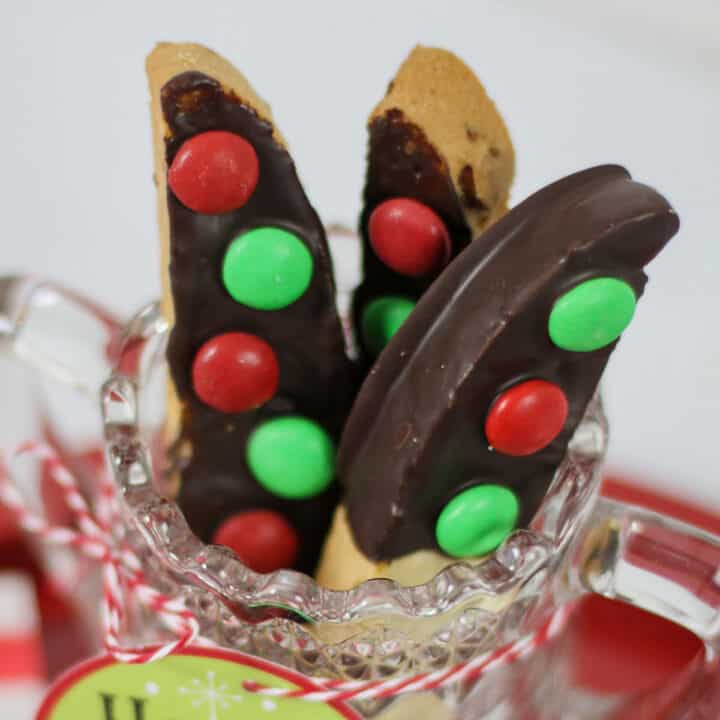 chocolate dipped biscotti with red and green m&m's standing in glass jar.