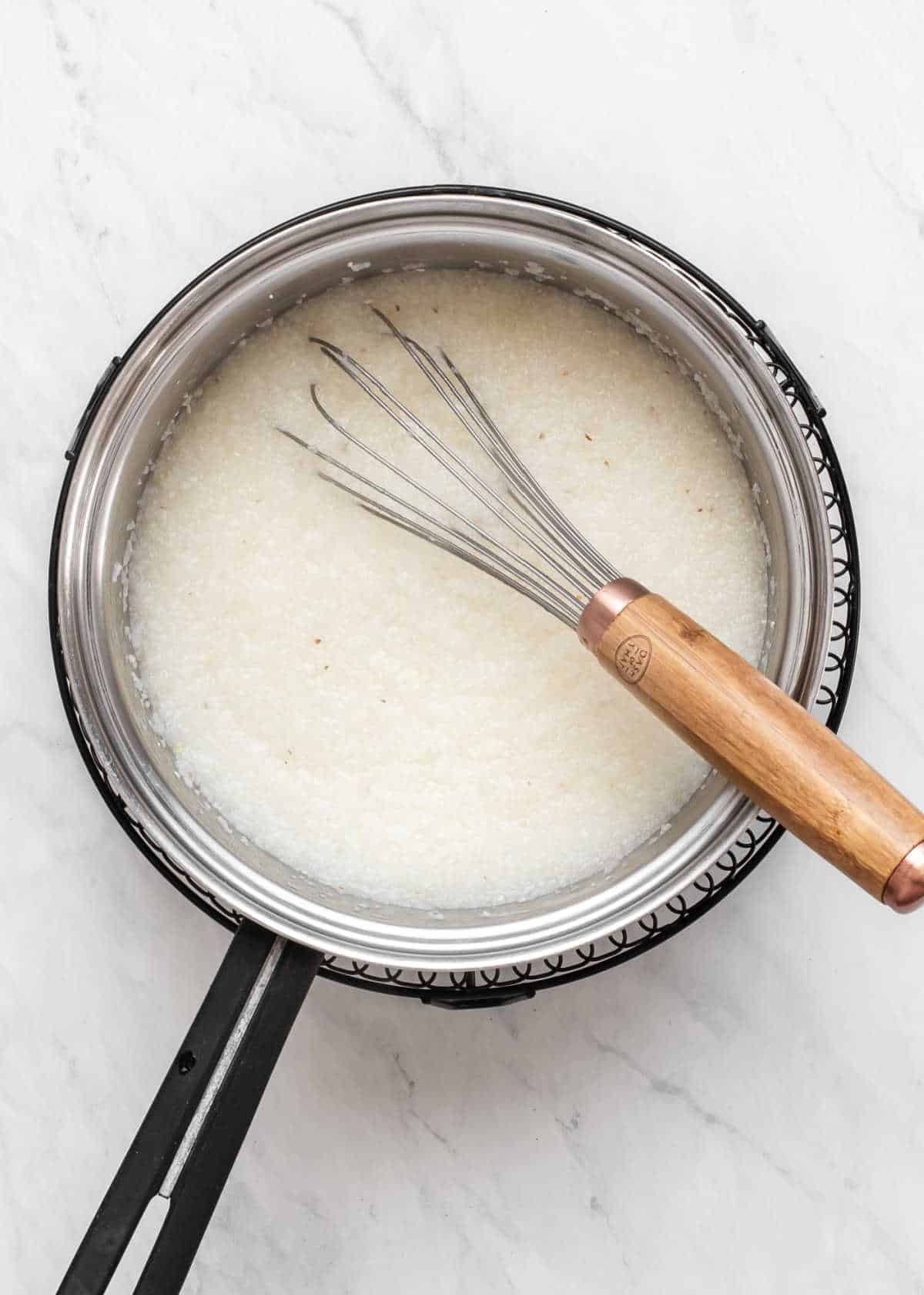 quick cooking grits in pot with whisk, overhead view.