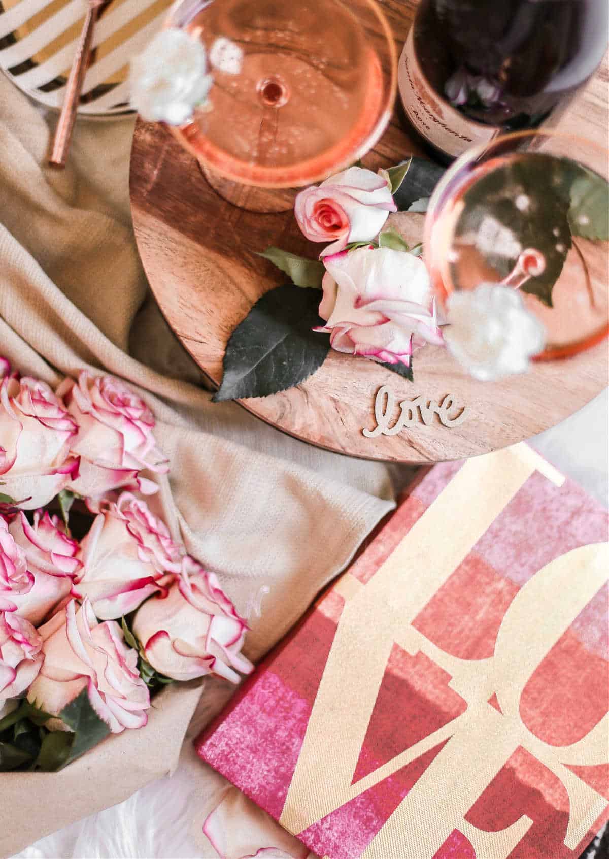 overhead view of LOVE sign, pink roses, and champagne cocktails.
