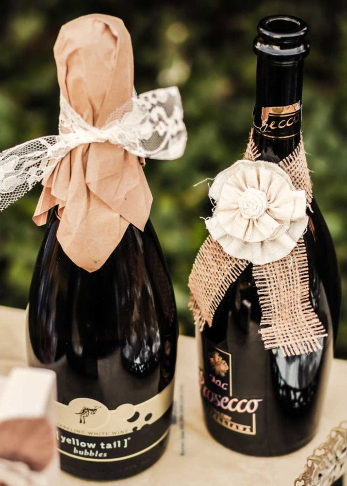 champagne bottles wrapped with vintage lace, burlap strips, and fabric flowers.