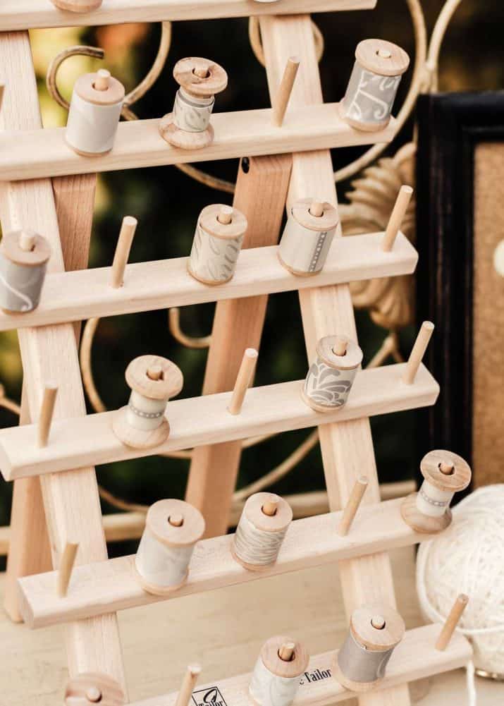 wood sewing spool holder with spools wrapped in decorative paper.
