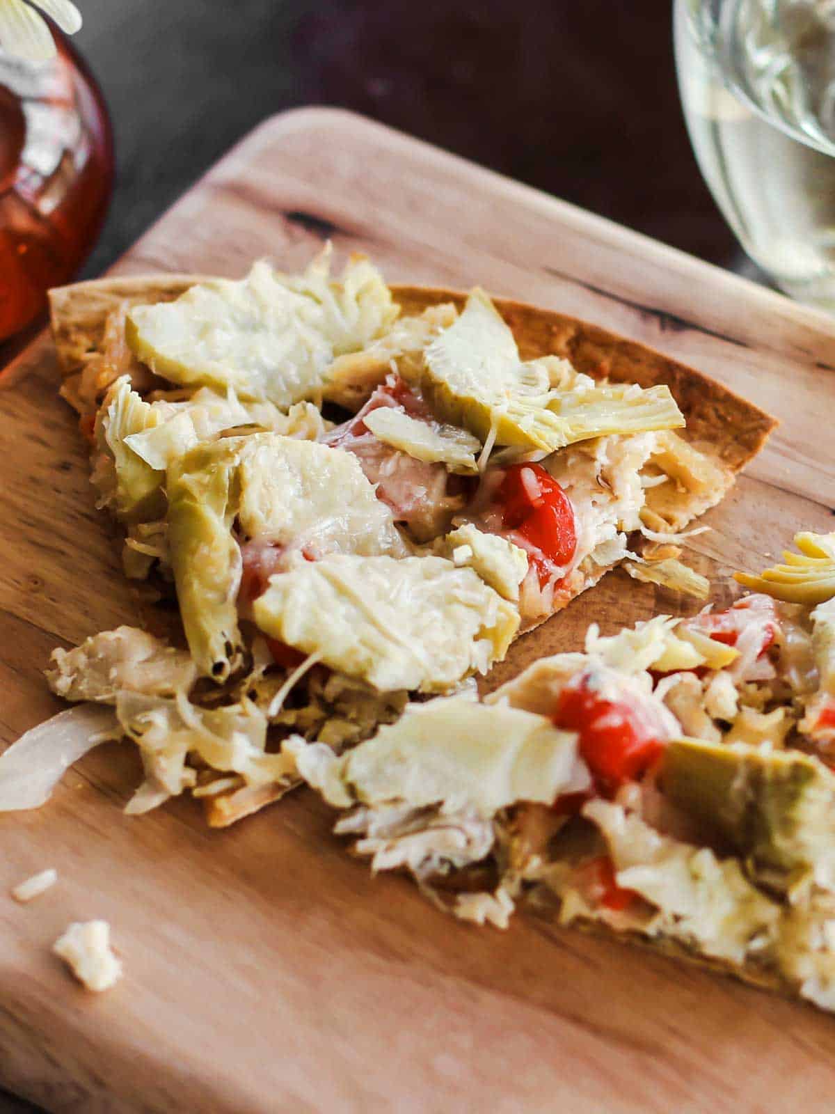 thin crust pizza slices with chicken and artichokes.