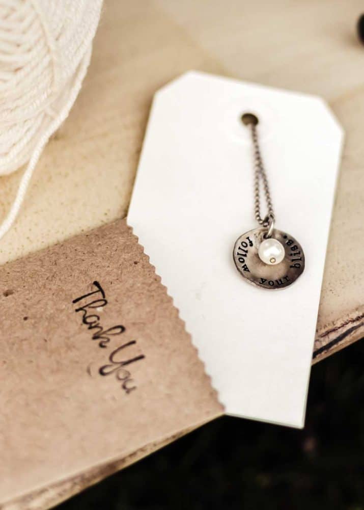 small sack with Thank You stamped on it, holding a card with necklace attached.