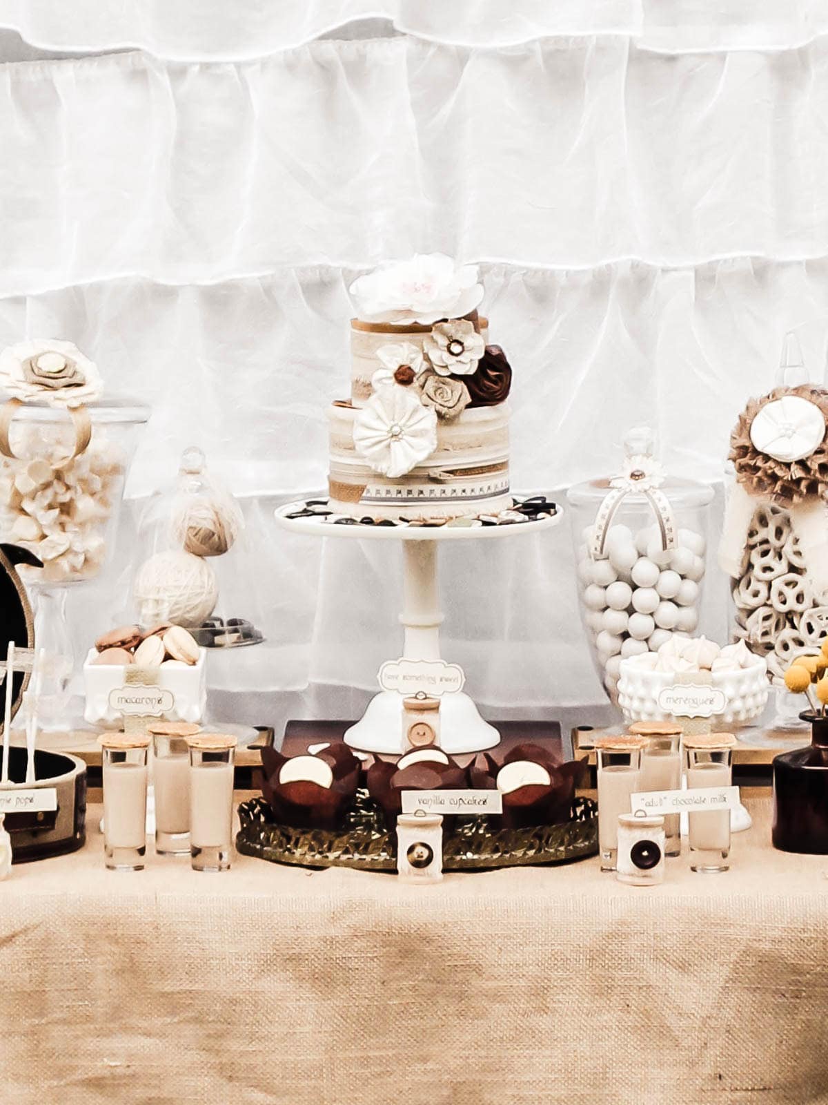 shabby chic decorated dessert table with white and tan and brown color scheme.