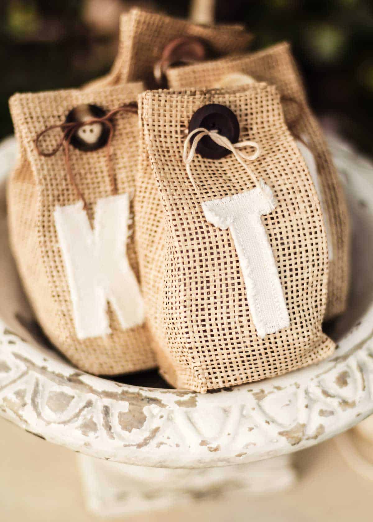 shabby chic urn holding burlap gift bags with canvas monograms attached.