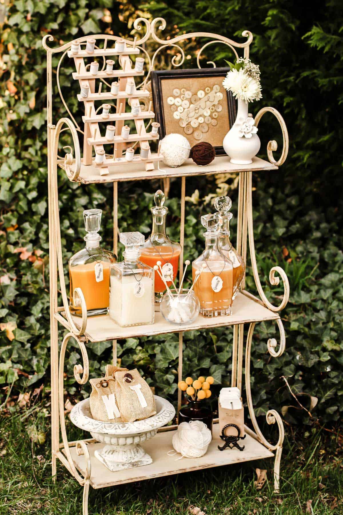 open metal shelf set up outside, with shabby chic decorations, punch decanters, and party favors.