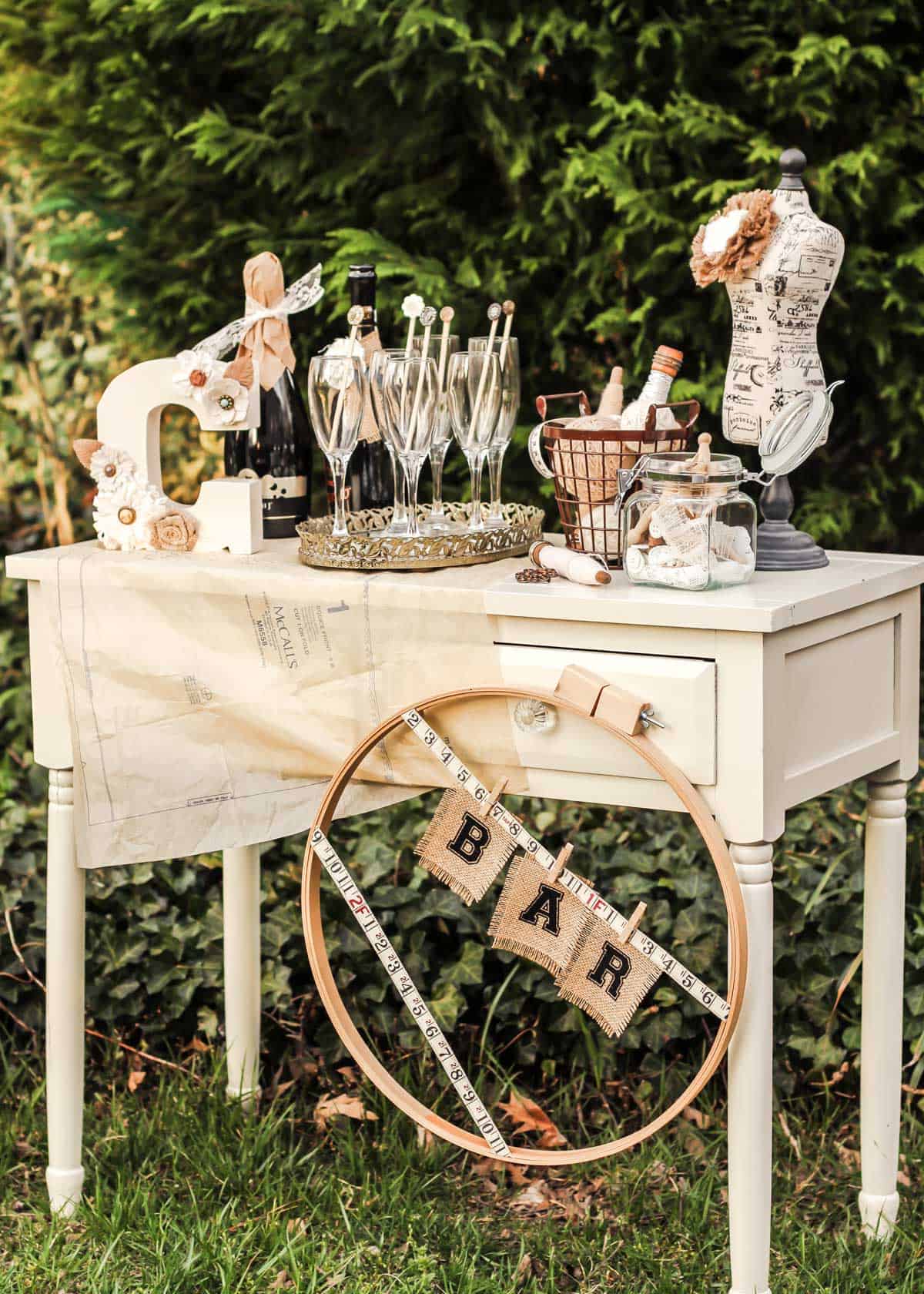 small console table set up outside with shabby chic decorations, champagne, and glasses. 