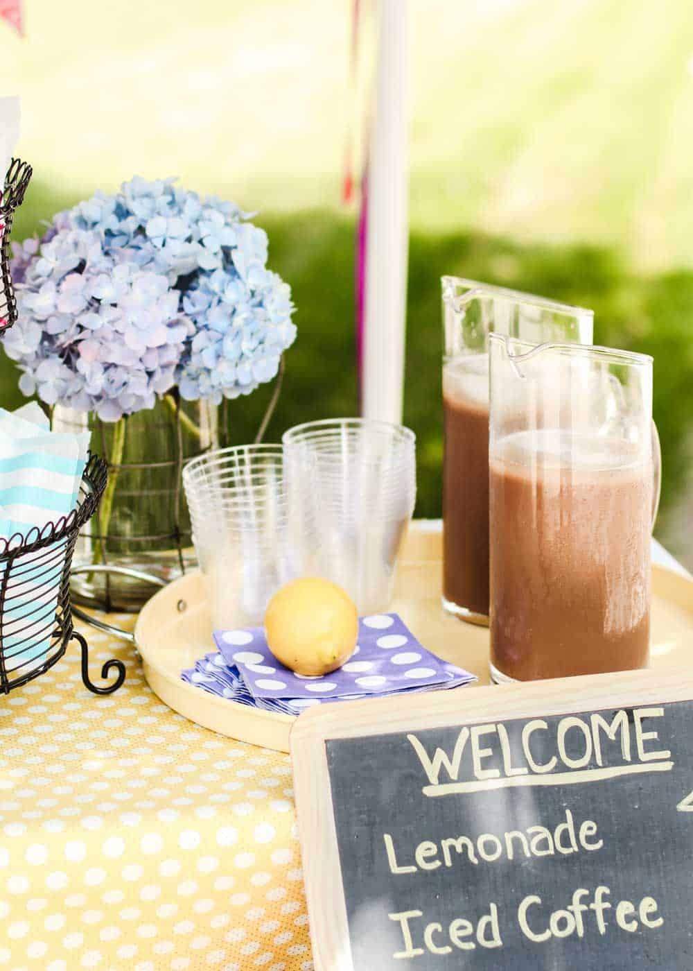 outdoor table with pitchers of iced coffee on a tray with clear cups.