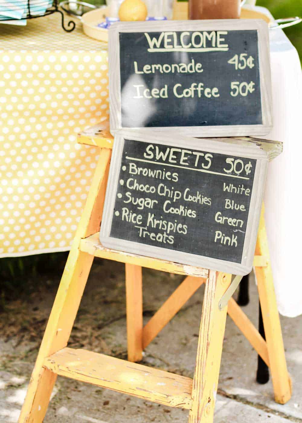 chalkboard signs sitting on a vintage step ladder with prices for a lemonade stand.
