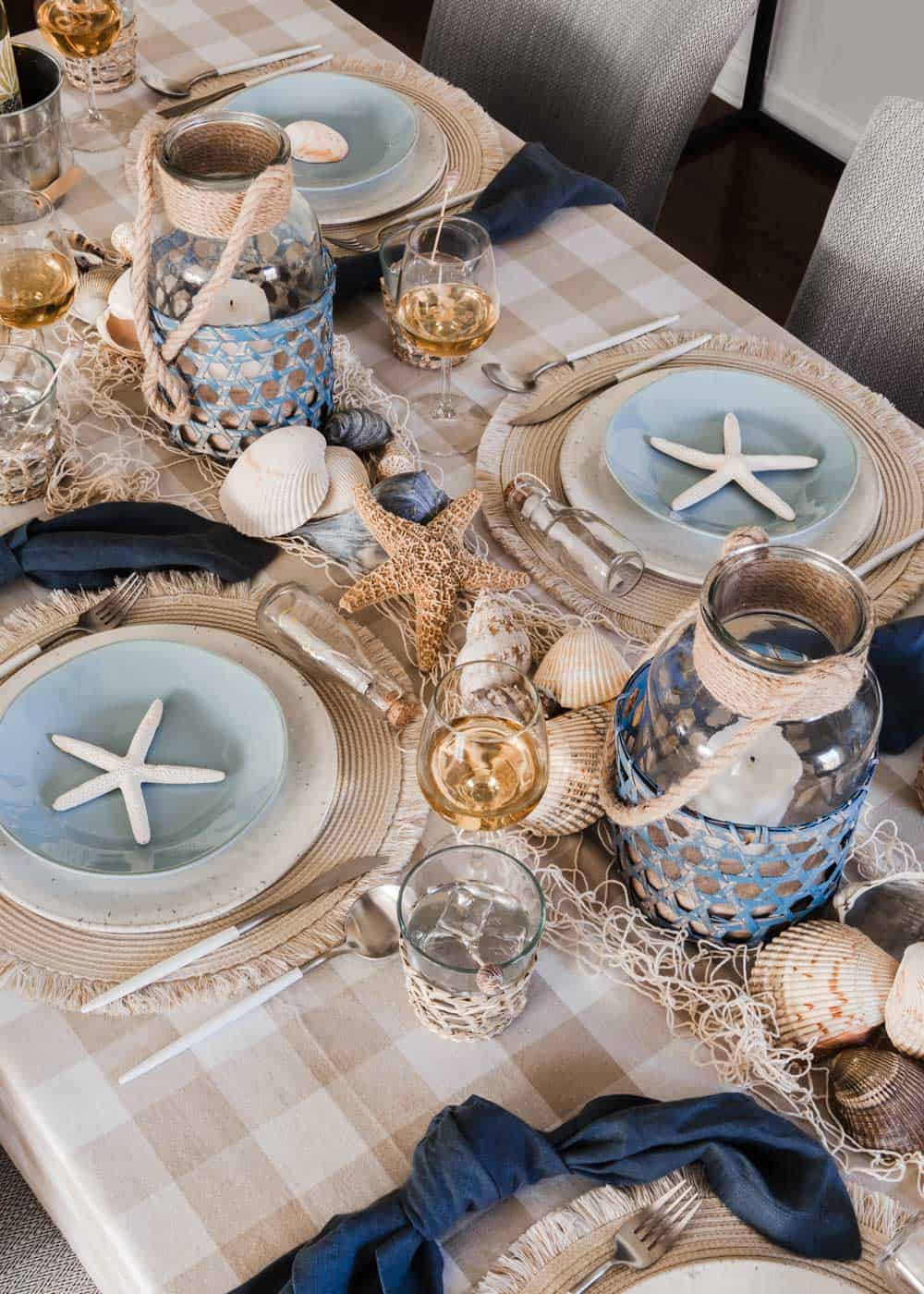 nautical themed tablescape with shells and candle holder centerpiece. 