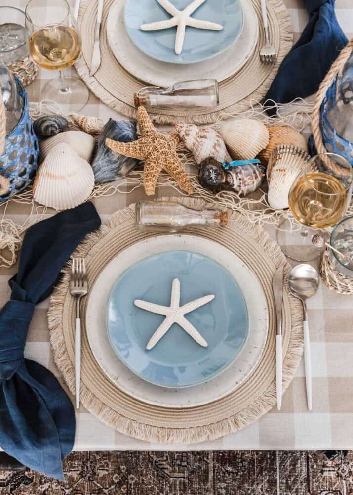 nautical dinner party place setting with starfish, shells, and blue and tan colors.