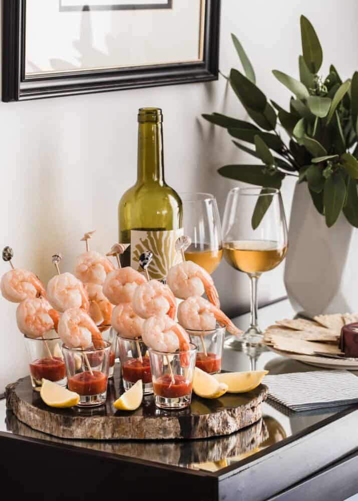 small table set up with shrimp cocktail skewers and wine.