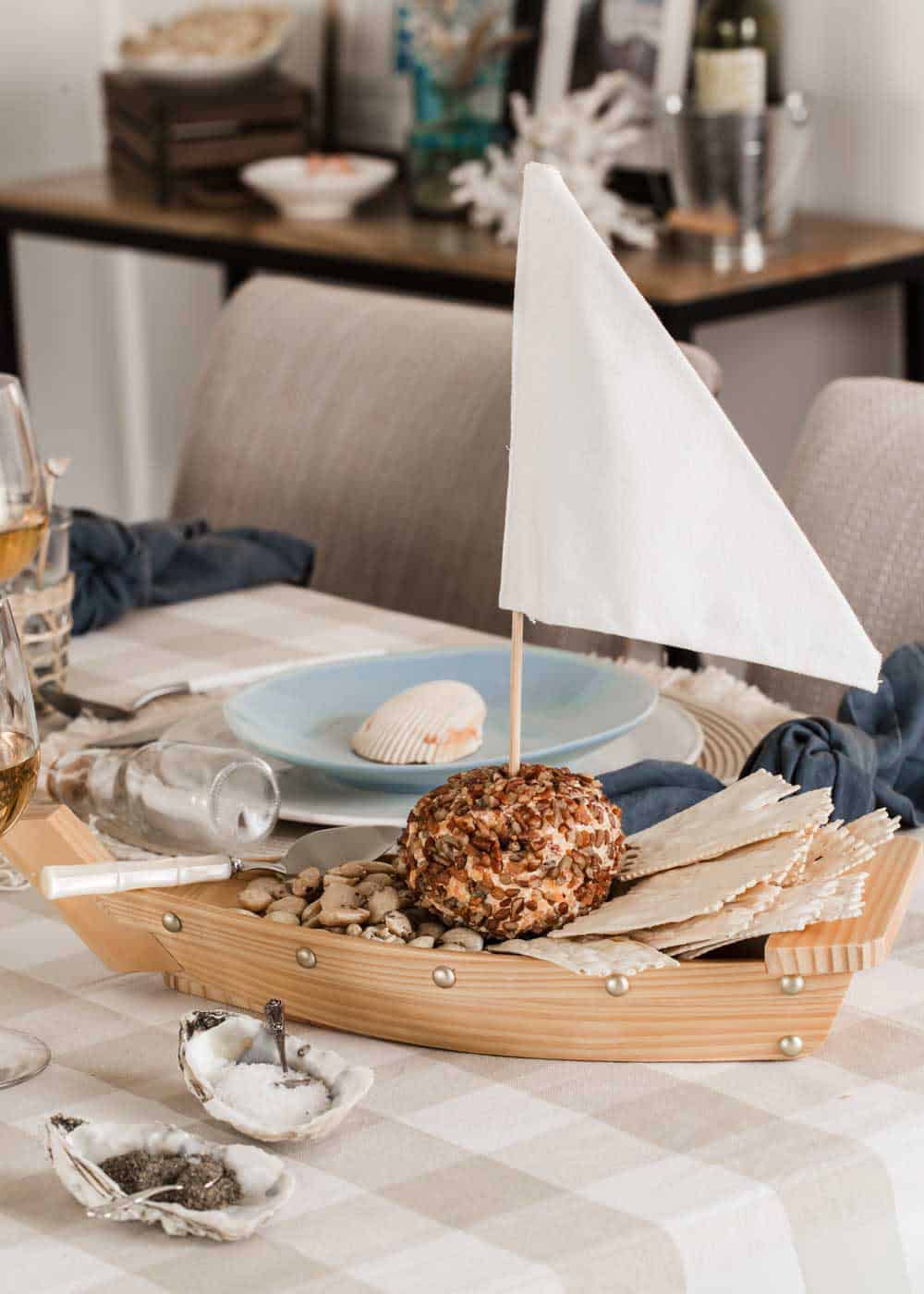 small wooden boat server with cheese ball and crackers inside.