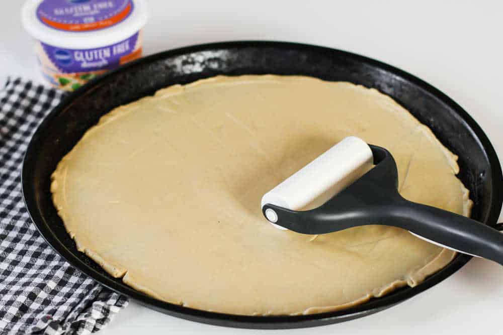 thin pizza dough rolled out on round baking sheet.