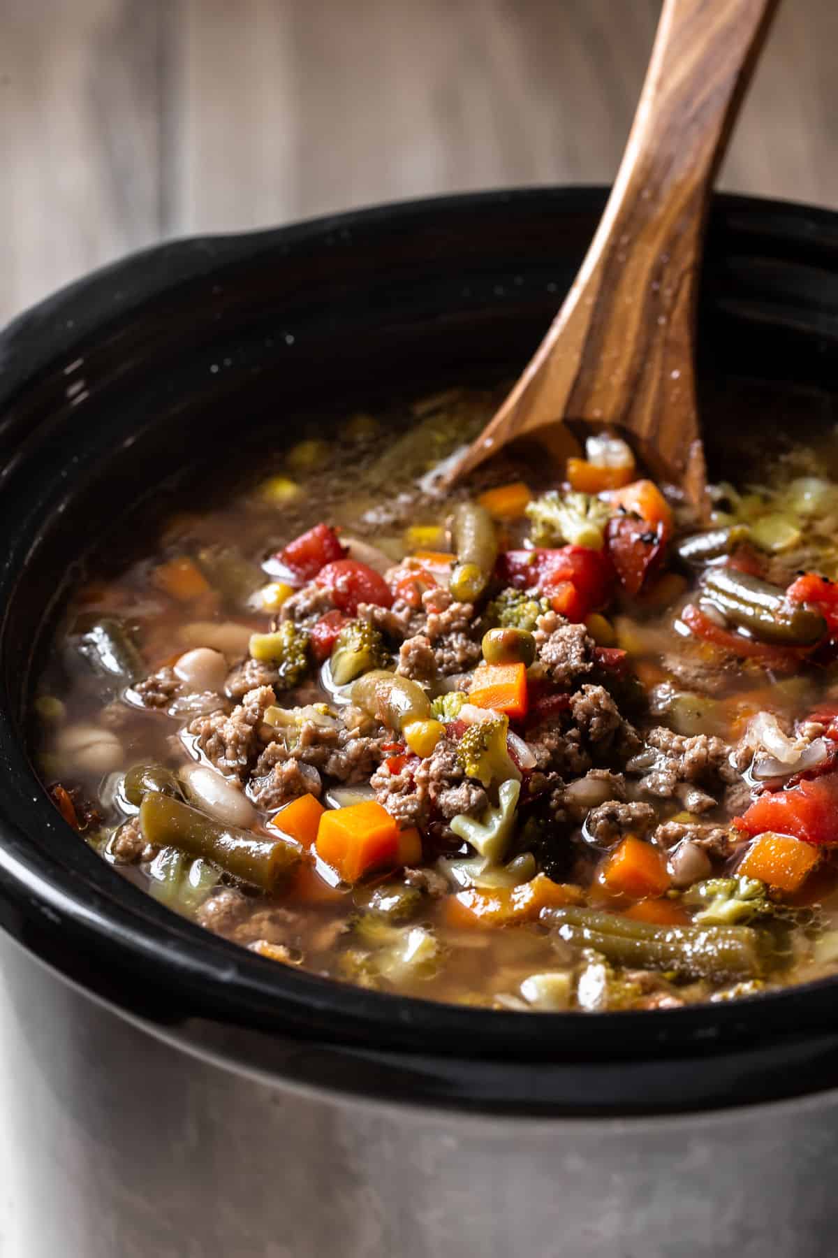 crock pot with ground turkey and vegetable soup and wood ladle inside