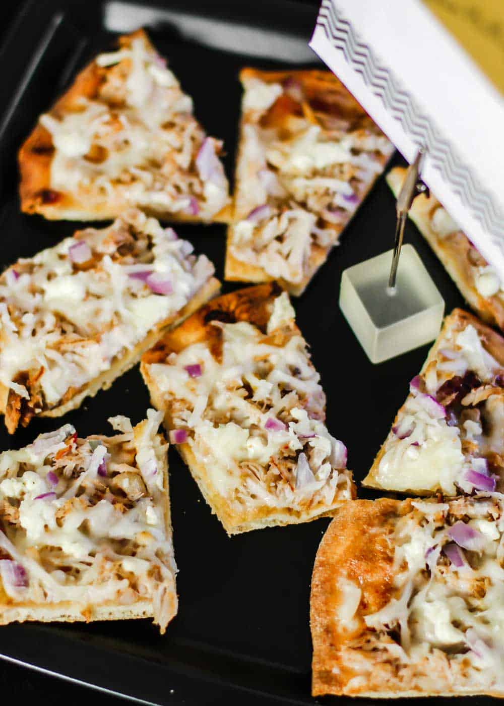 slices of pizza with white sauce and crab meat, on black platter.