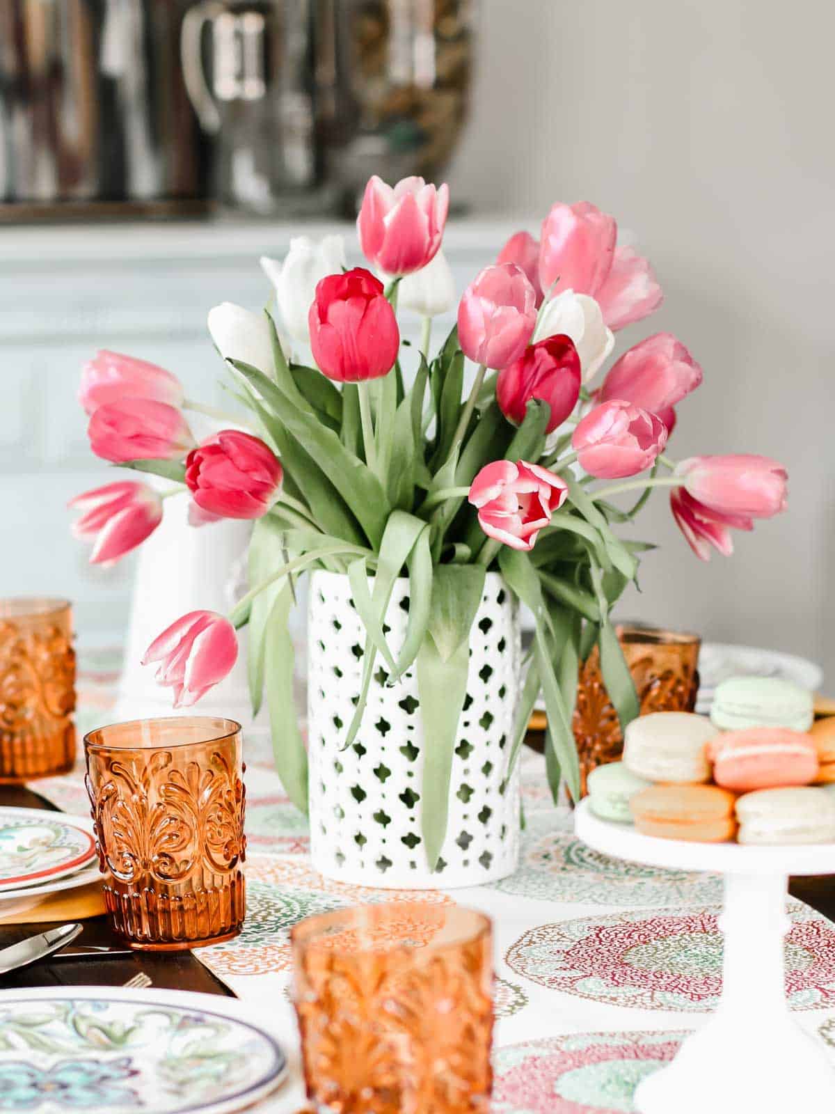 white vase filled with pink tulips, centerpiece on dining table.