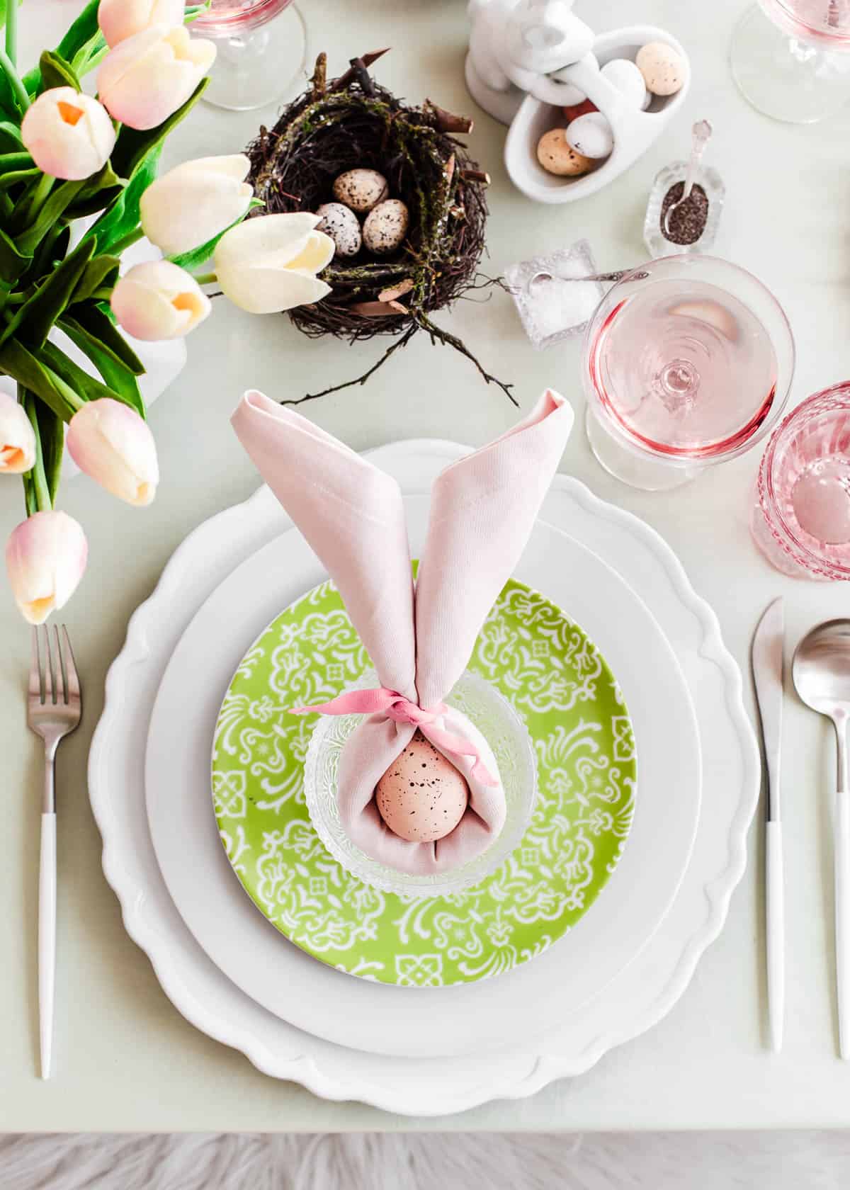 pink and green Easter table setting with napkin folded like bunny ears.