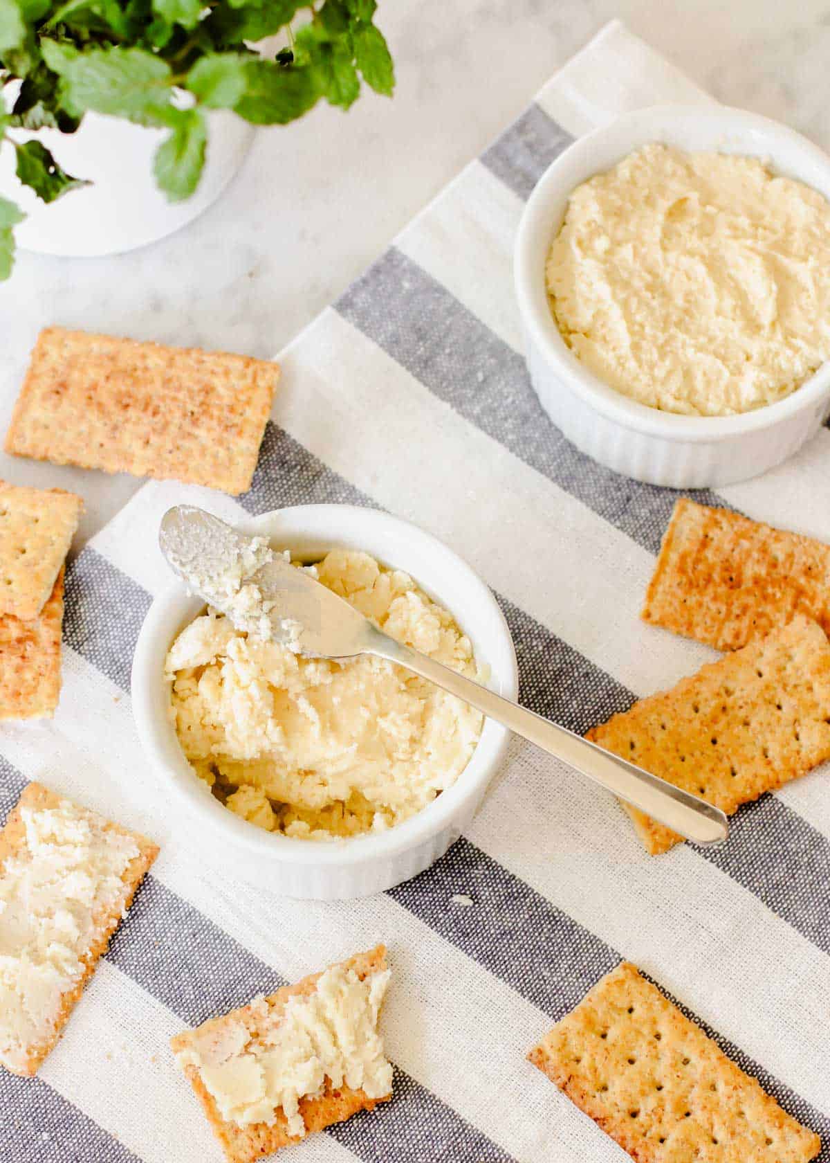 two ramekins filled with beer cheese spread surrounded by club crackers.