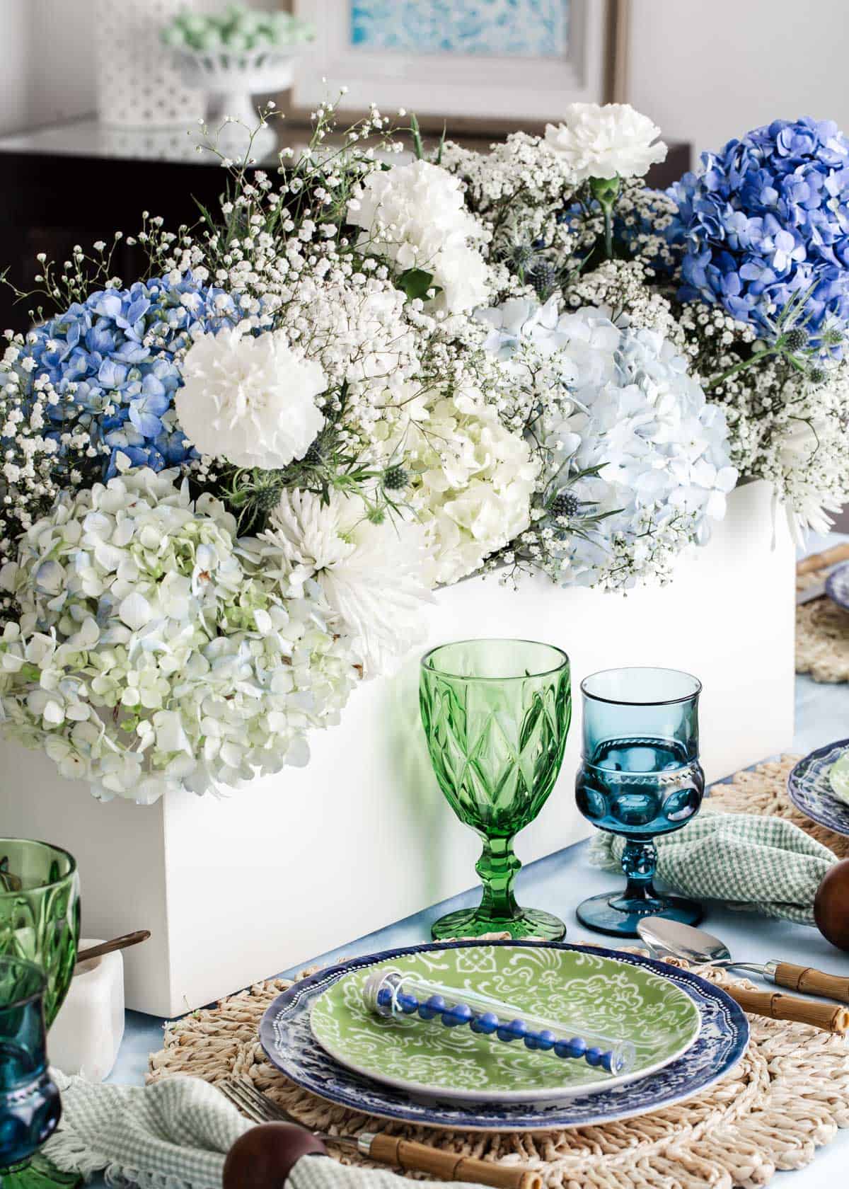 large white flower box centerpiece with blue hydrangeas and white flowers, on tablescape.