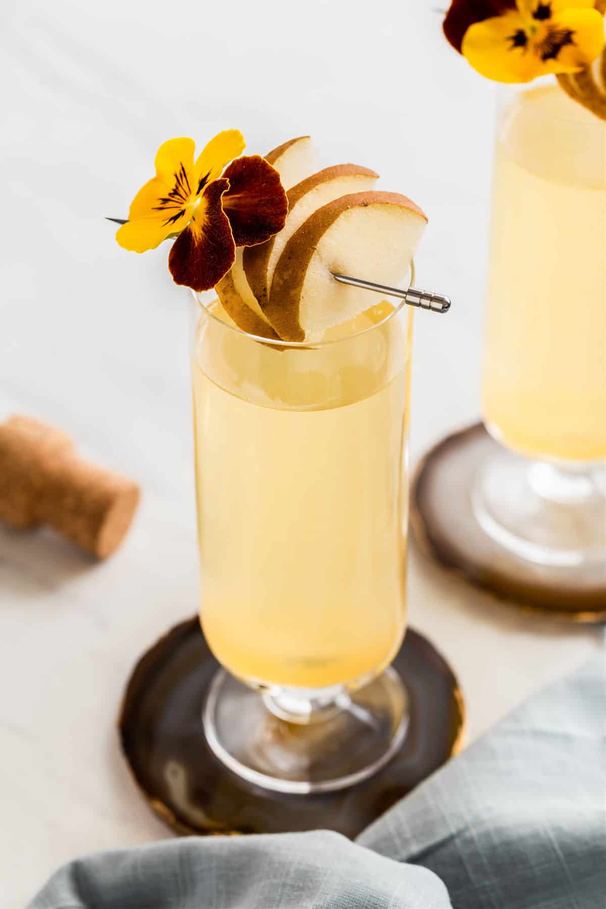 pear prosecco drink in flute glass with pear and flower garnish