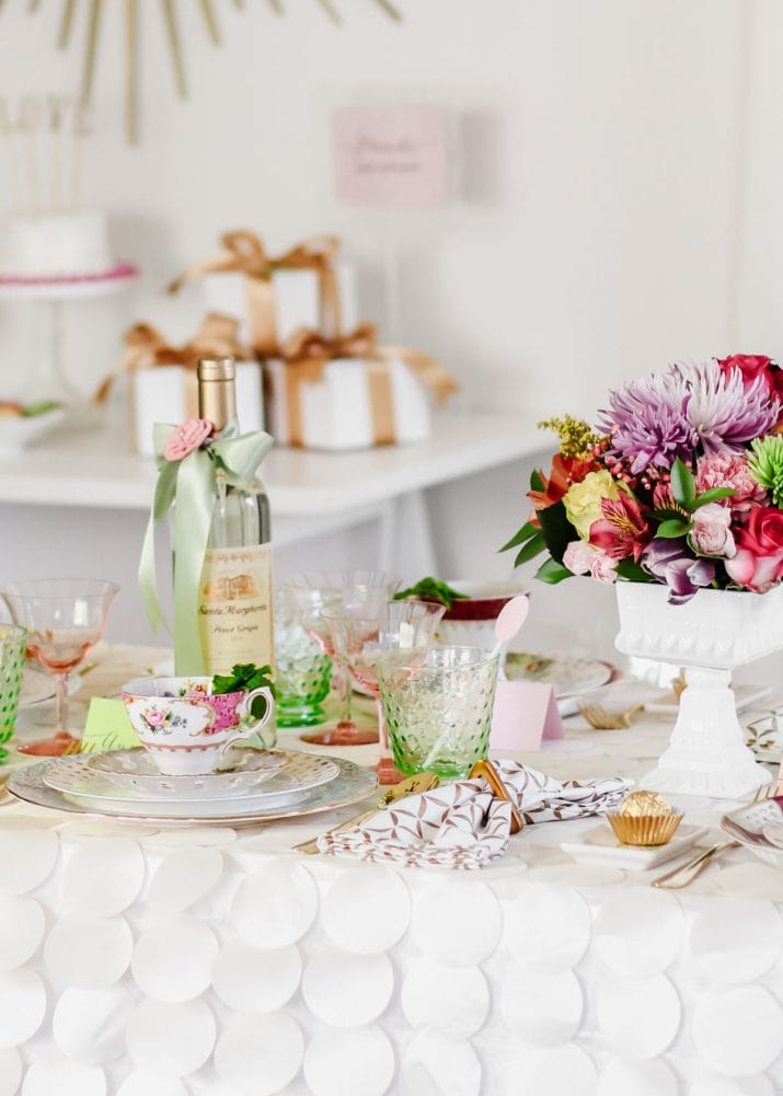 feminine style party decor with floral china, colorful flowers centerpiece, and vintage glasses.
