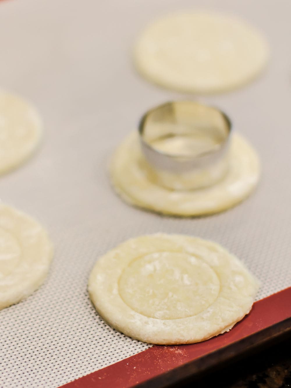 small biscuit cutter cutting into pastry dough circles.