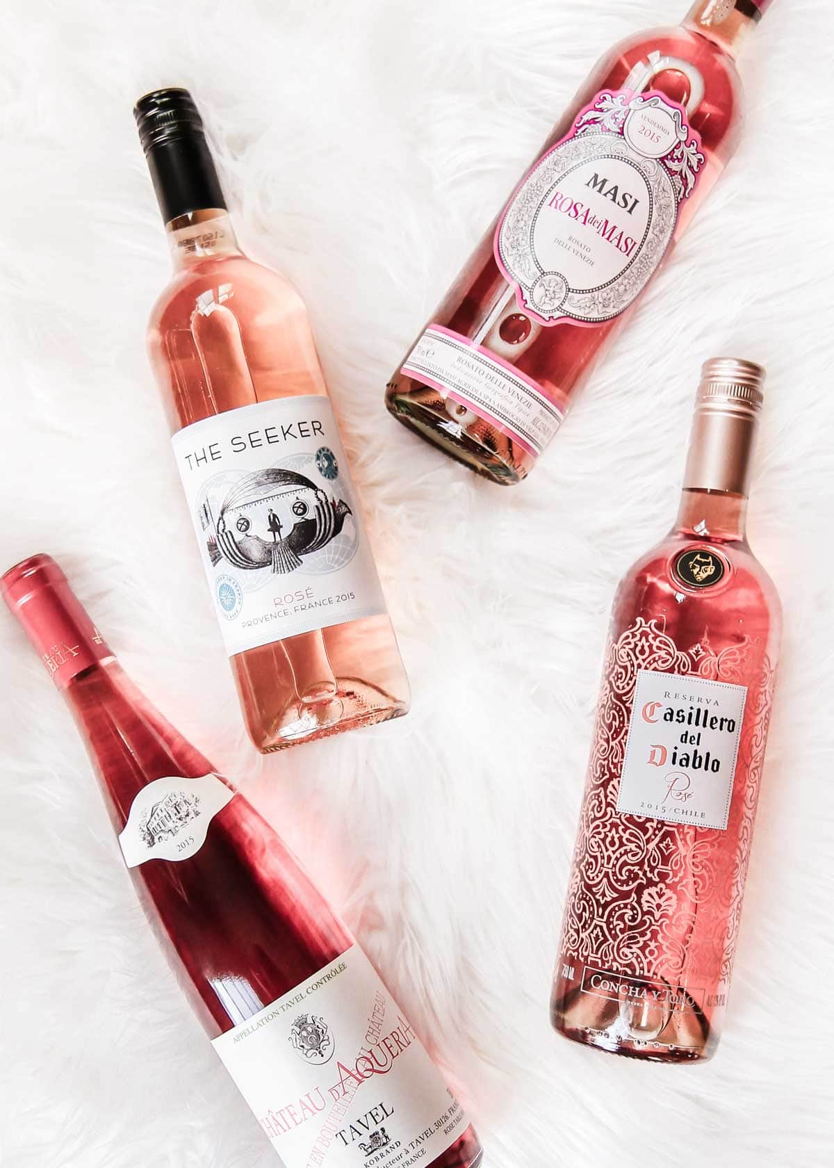 four bottles of Rosé wine laying on white background.