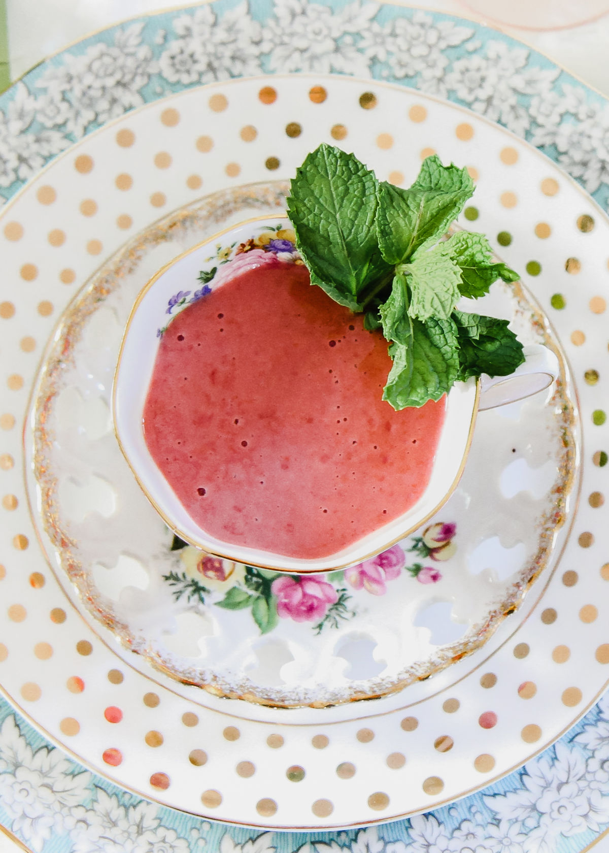 raspberry soup in tea cup with mint garnish.