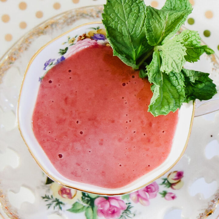 pink soup in tea cup with mint garnish.
