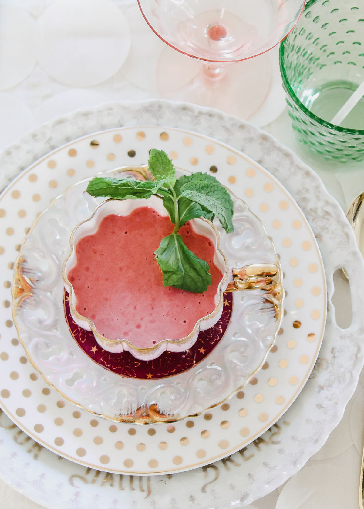 pink soup in tea cup on place setting, garnished with mint.