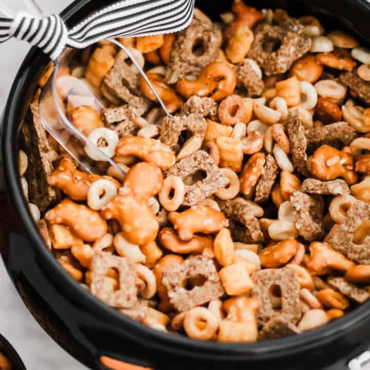snack mix in black bowl with scoop inside.