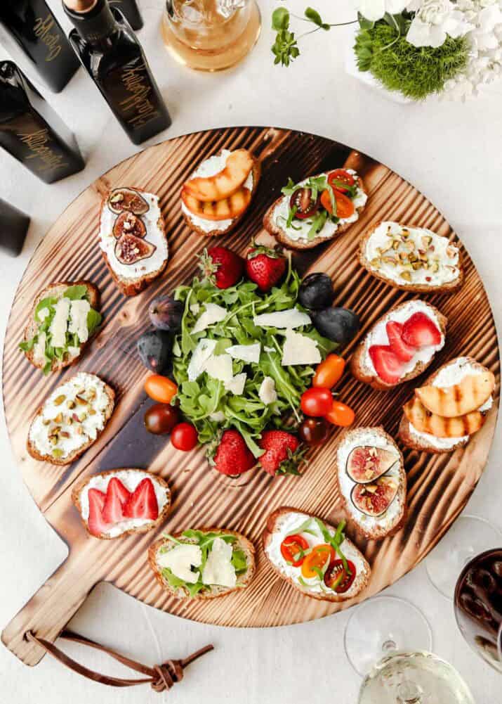 large round board display of crostini appetizers with various toppings.