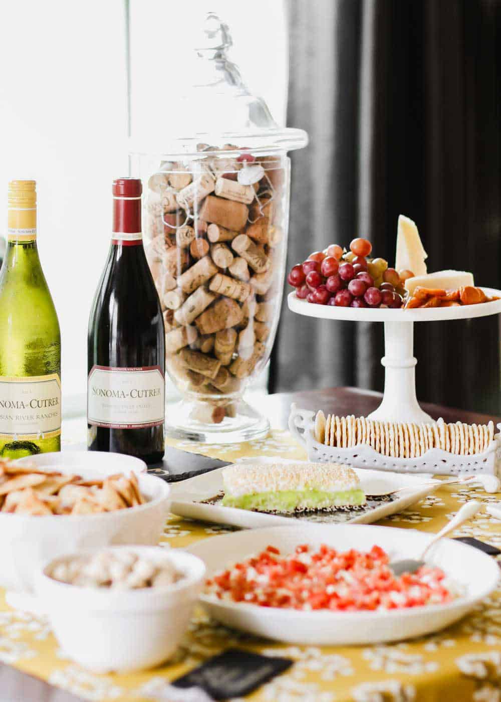 table set with appetizers and wine in white serving dishes.