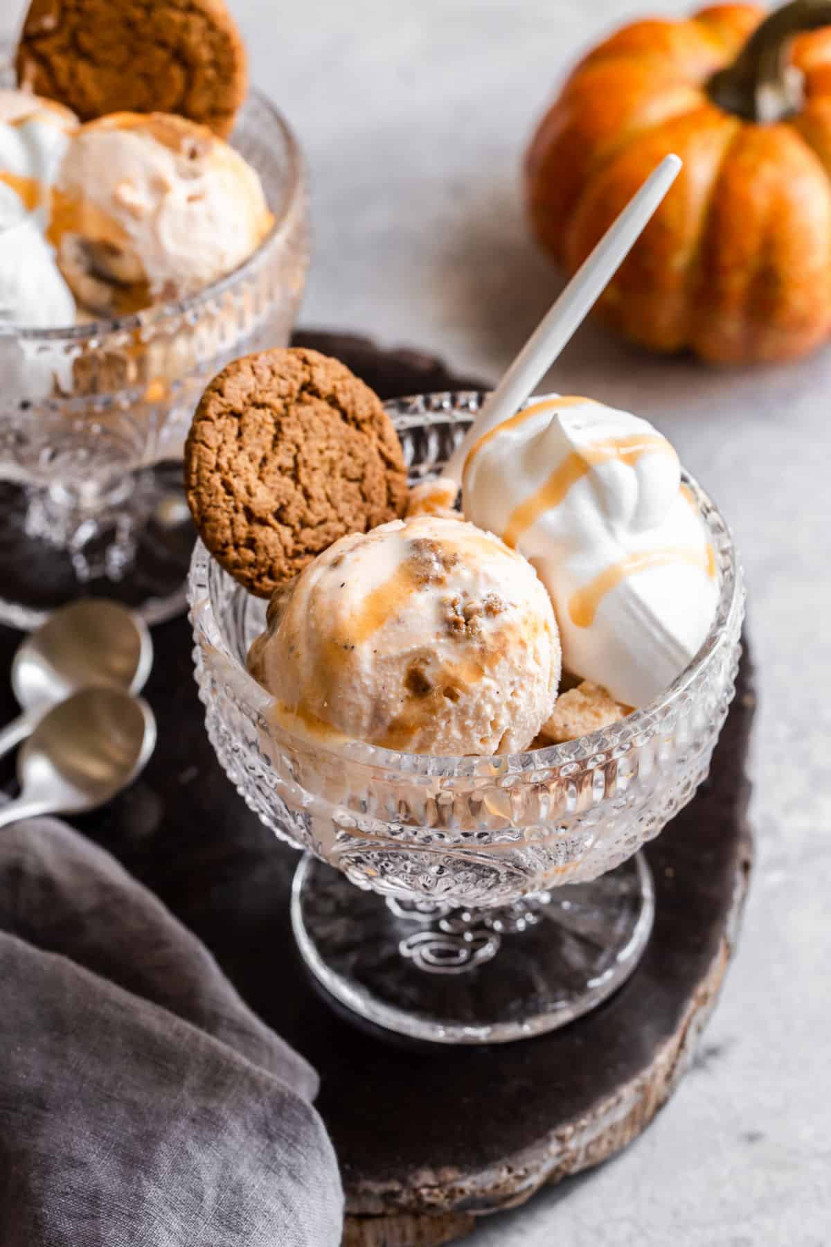 glass footed dish with ice cream, whipped cream, and ginger snap cookie