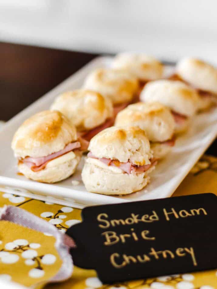 ham and cheese biscuit sandwich appetizers on white platter.