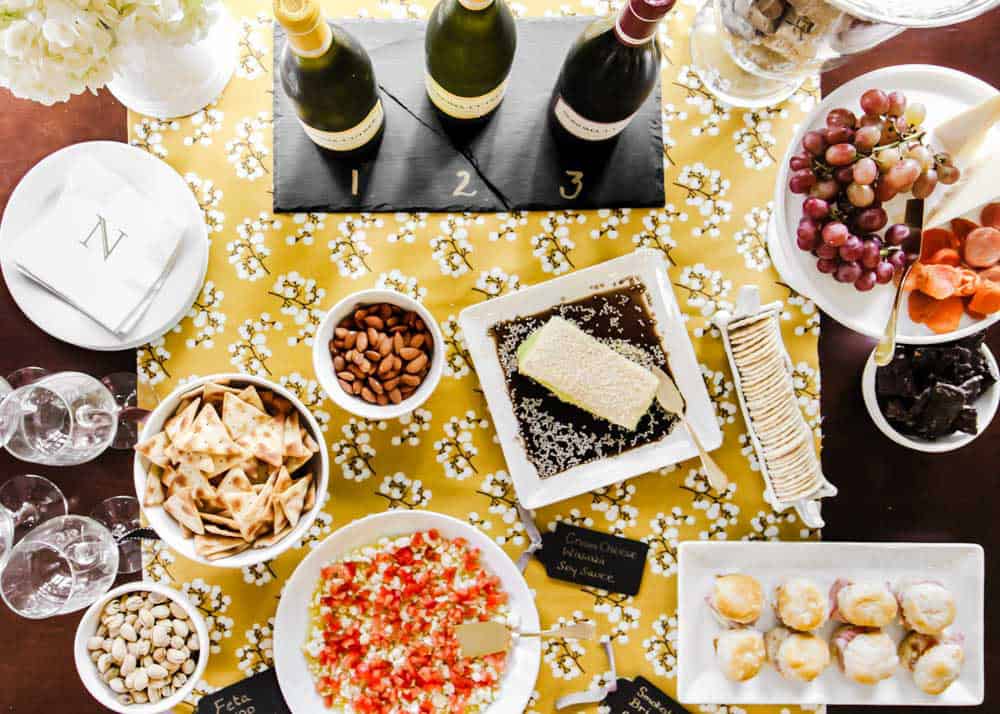 party table buffet with wine and appetizers served on white dishes.