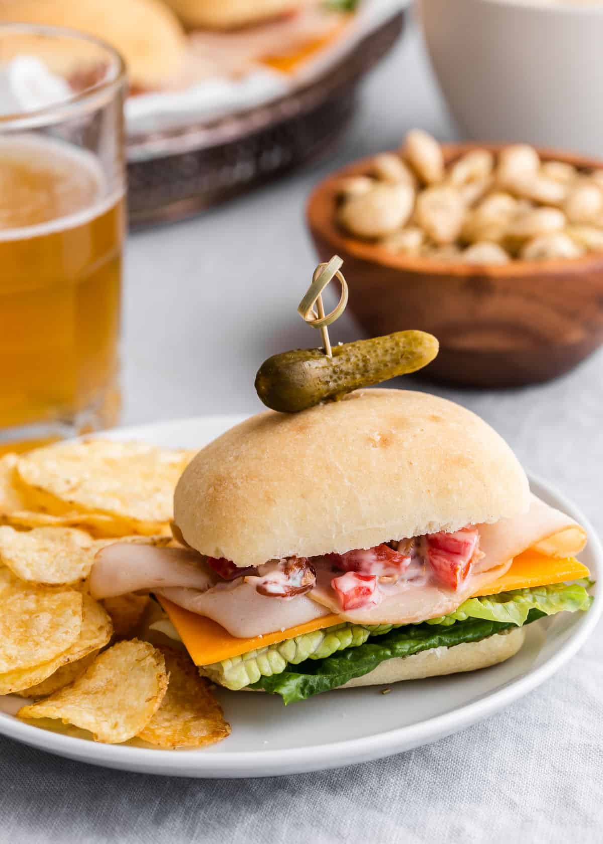 mini blt sandwich on plate with potato chips and beer.