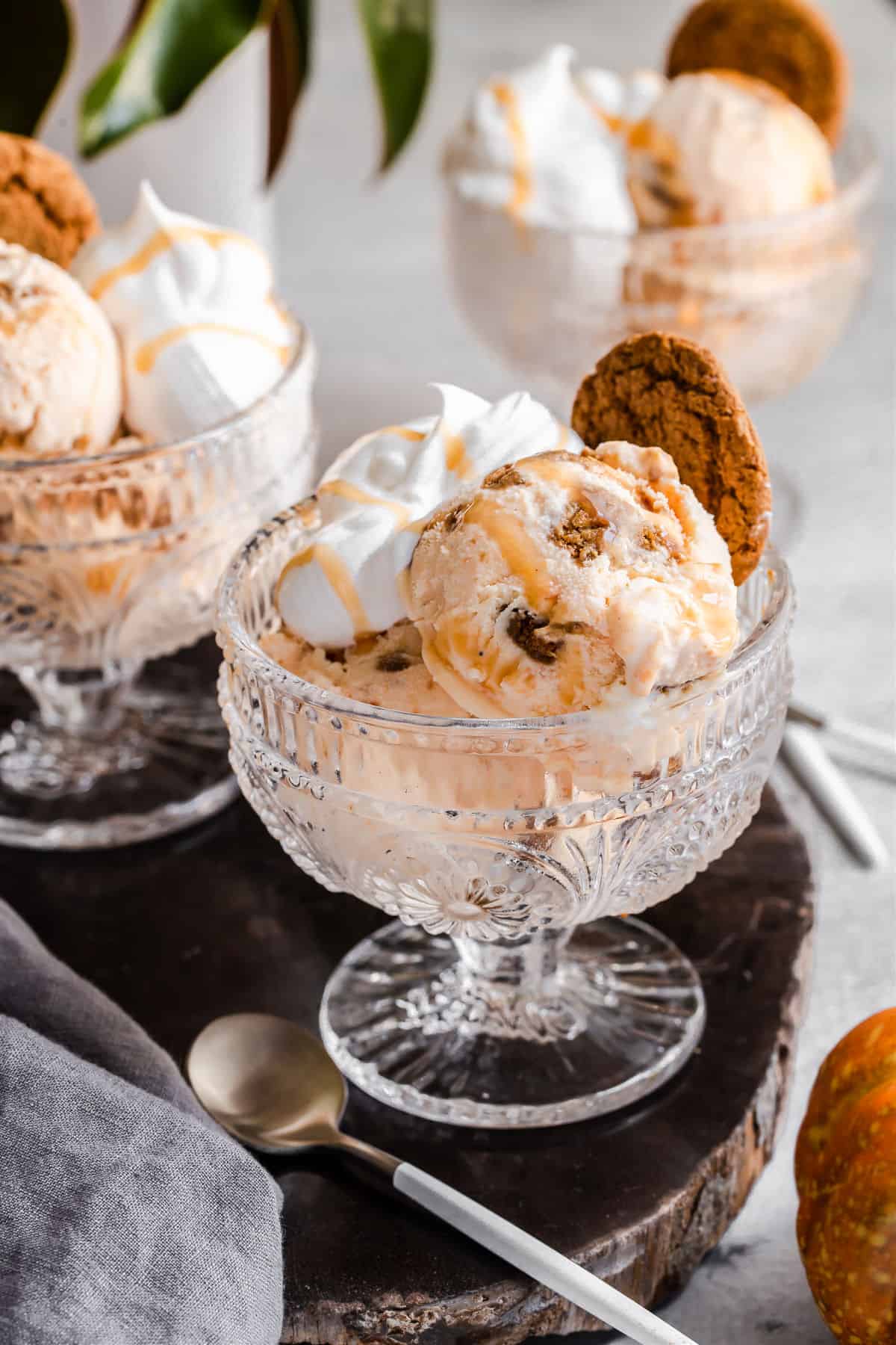 small glass compote with pumpkin ice cream inside, whipped cream, and cookie