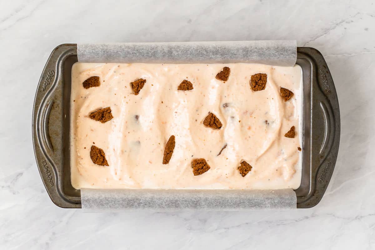 ice cream poured inside loaf pan with cookie pieces on top