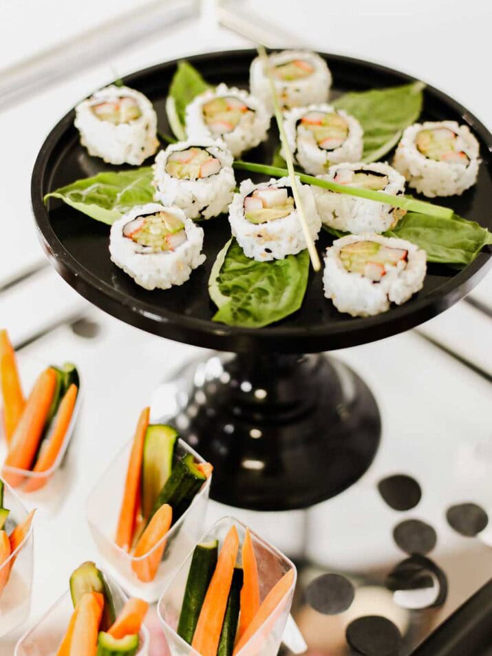 California rolls displayed on a black cake pedestal, with basil leaf garnish.