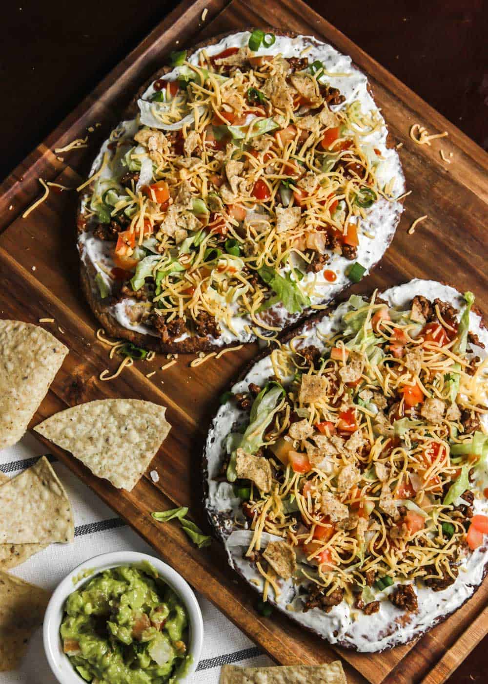 two Mexican topping pizzas on wood board.