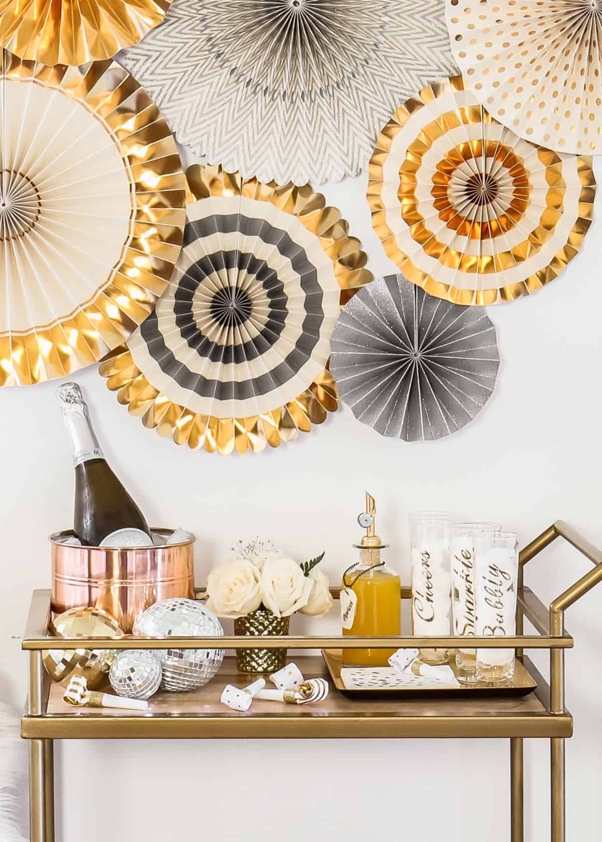 bar cart with champagne and paper fans decor above