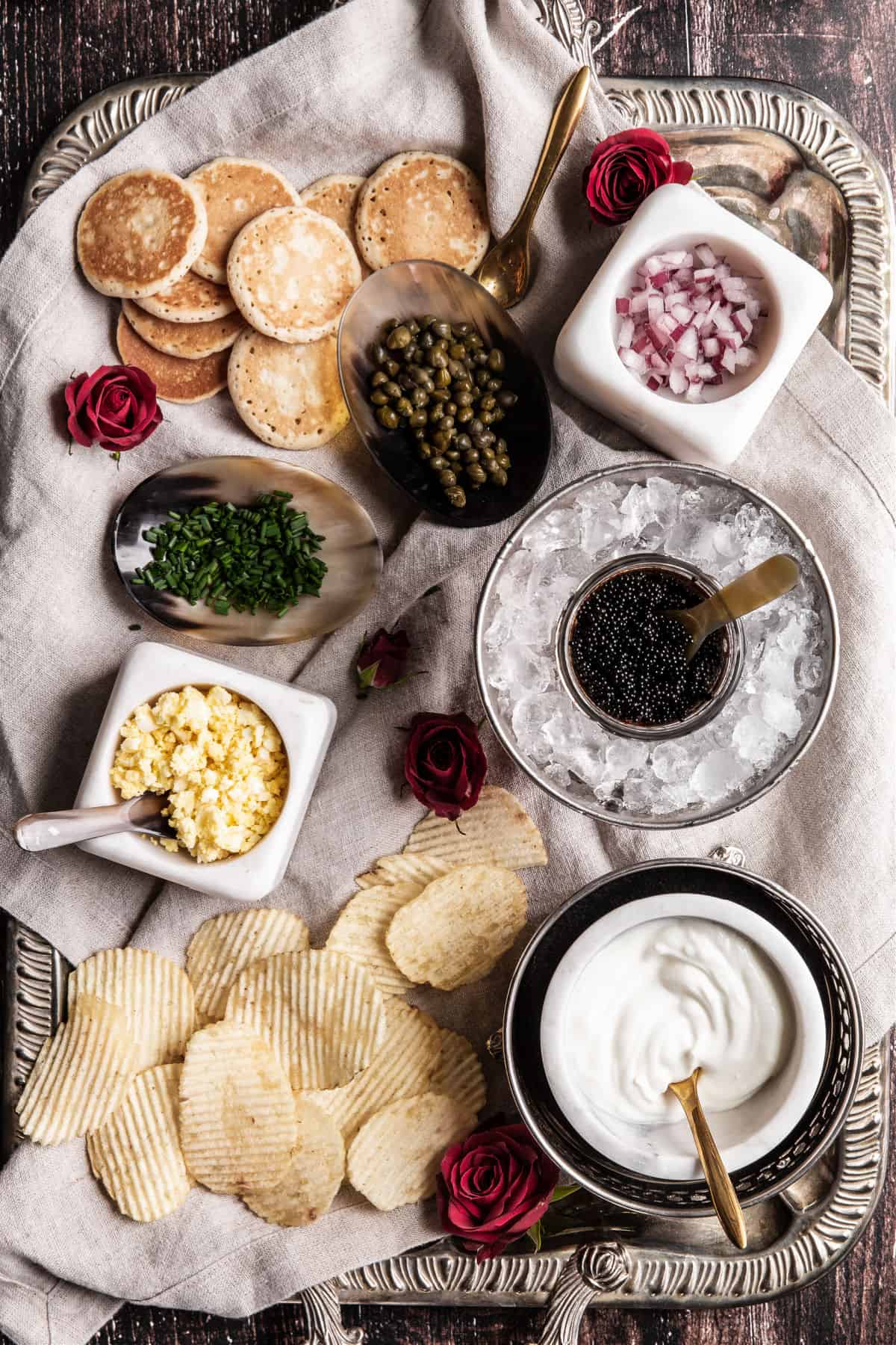 silver tray with caviar, potato chips, and toppings
